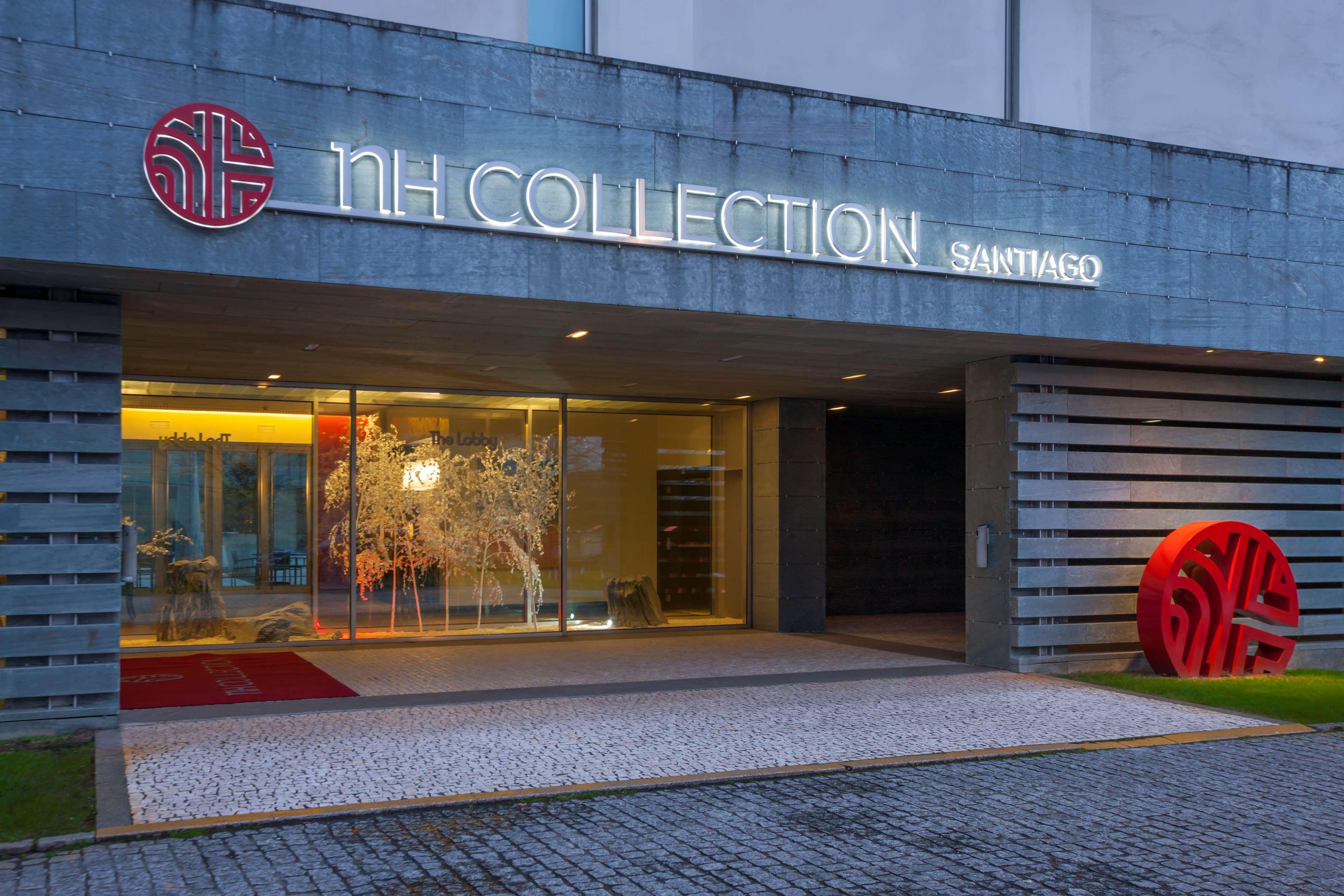 Nh Collection Santiago De Compostela Hotel Exterior photo The image shows the entrance of the NH Collection hotel in Santiago. The facade features a modern design with concrete and large glass doors. The hotel name, "NH COLLECTION SANTIAGO," is prominently displayed in illuminated letters. There is a decora
